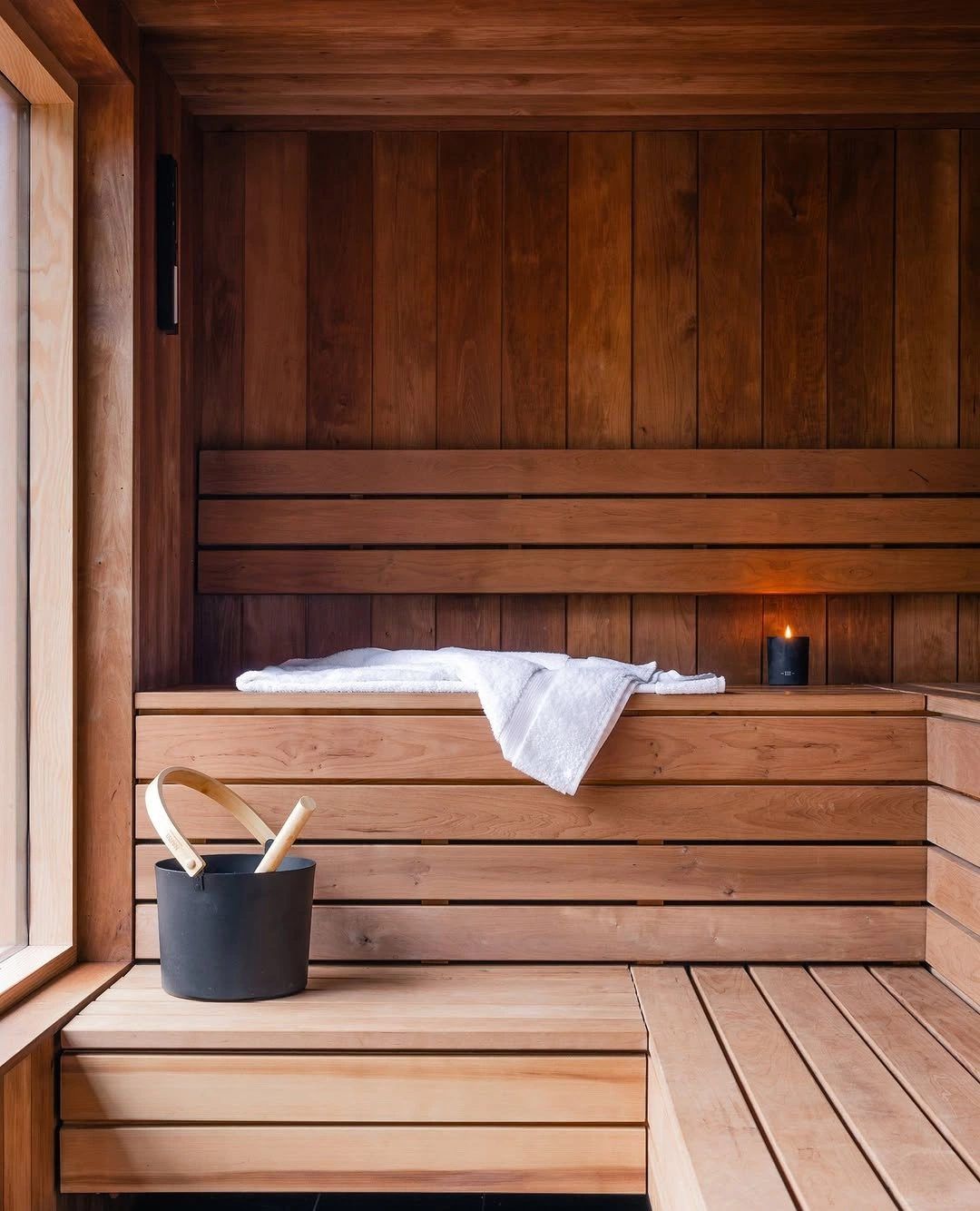 Empty wooden sauna with towel, bucket and candle